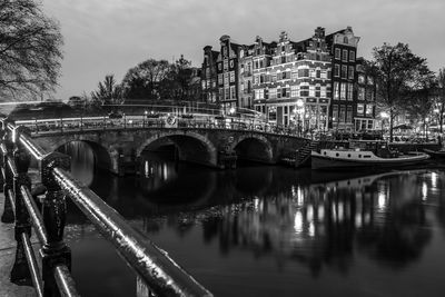 Bridge over river in city against sky