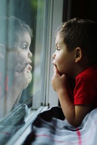 Portrait of boy looking through window