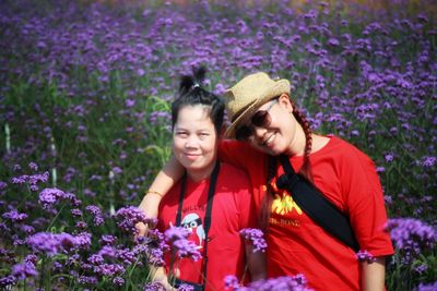 Portrait of a smiling young woman against purple flowering plants