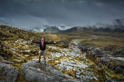 Rear view of man standing on mountain against sky