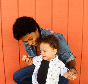 Mother and son with against orange wall