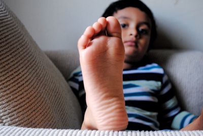 Close-up of baby girl sitting on sofa at home