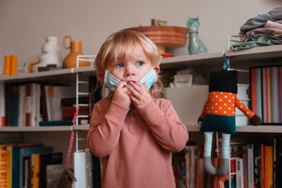 Close-up of cute girl wearing mask at home