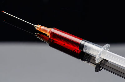 High angle view of blood in syringe on table against black background