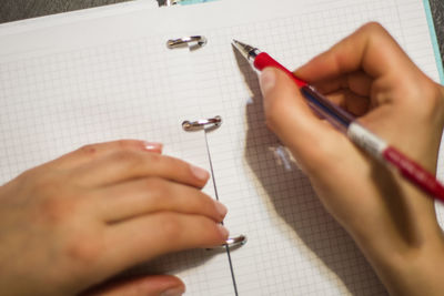 Cropped hand of person writing on book