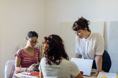 Group of young businesswomen at table discussing plan