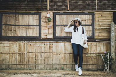 Woman in sunglasses standing against barn