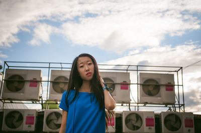 Portrait of young woman standing against exhaust fans