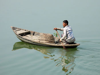 Rear view of man rowing boat in river 