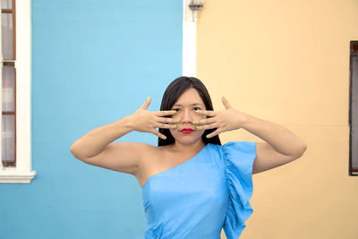 Portrait of young woman standing against wall