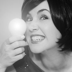 Close-up portrait of smiling young woman holding light bulb