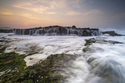 Scenic view of waterfall against sky during sunset