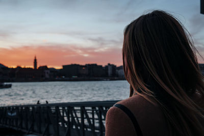 Rear view of woman looking at cityscape against sky