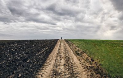 Tire tracks on agricultural field against sky