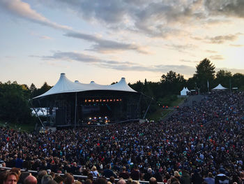 Crowd at music concert against sky during sunset