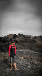 Rear view of man standing on mountain against sky