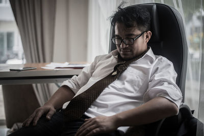 Tired mid adult businessman relaxing on chair in office