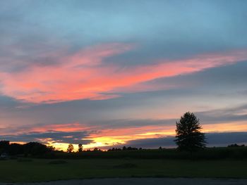 Silhouette trees on field against romantic sky at sunset