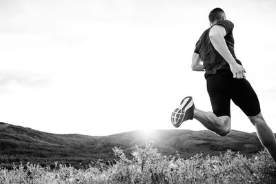 Low angle view of man running on land against clear sky