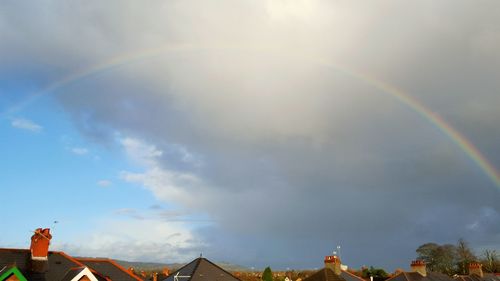 Rainbow over residential district against sky