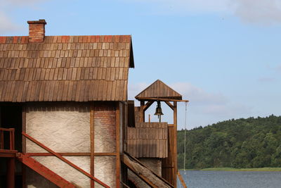 Built structure by lake and building against sky