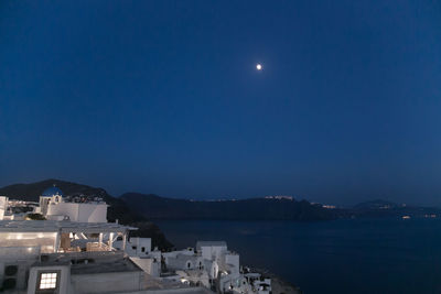 Town by sea against clear sky at night