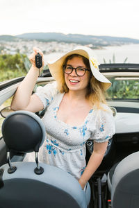 Portrait of smiling woman sitting on car