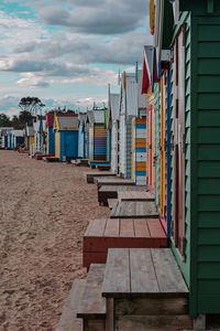 Chairs on beach by buildings against sky