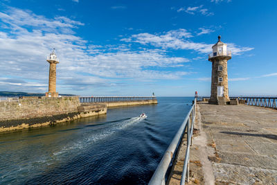 Lighthouse by building against sky