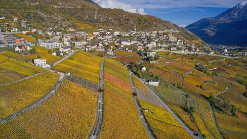 High angle view of field by buildings against mountains