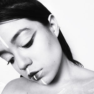 Close-up of young woman with make-up looking down against white background