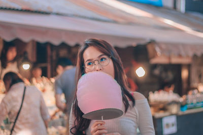 Young woman looking away while eating cotton candy