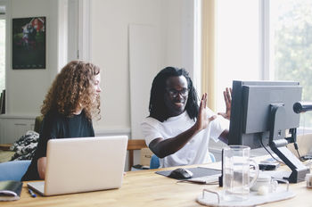 Young business people discussing over computer at table in creative office