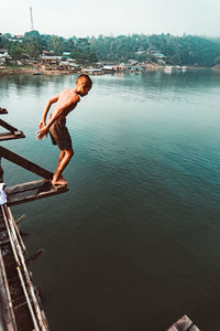 Full length of shirtless man jumping in lake