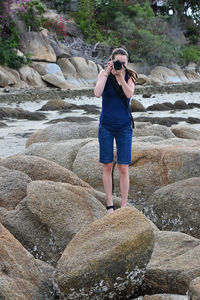 Full length of woman photographing while standing on rock