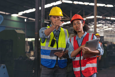 A portrait of a manufacturing worker in discussion with an industrial man and woman engineer 