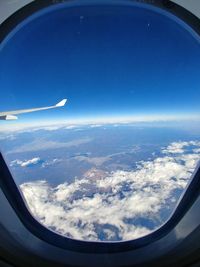 Aerial view of clouds over landscape seen from airplane window