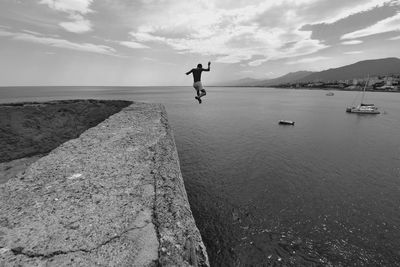 Man jumping over sea against sky