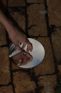 Cropped hand of woman gesturing over mirror on floor