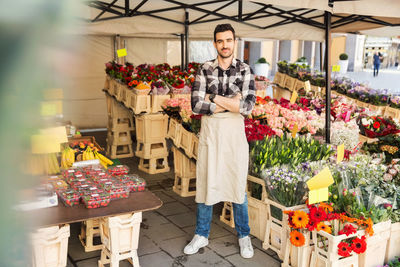 Full length portrait of confident male owner standing arms crossed in flower shop