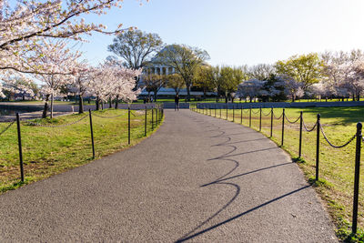 Footpath on field by jefferson memorial against clear sky