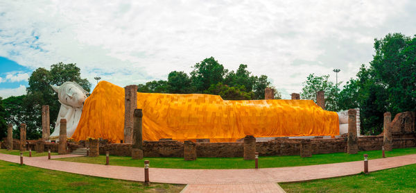 Buddha statue on field against sky