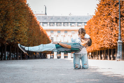 Gay couple kissing on road in city during autumn