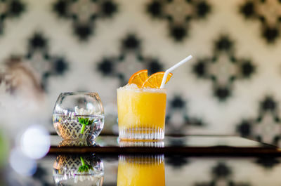 A glass of orange cocktail puts on table of the bar for holiday and summer drink concept.