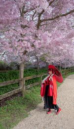 Full length of woman with pink cherry blossom tree