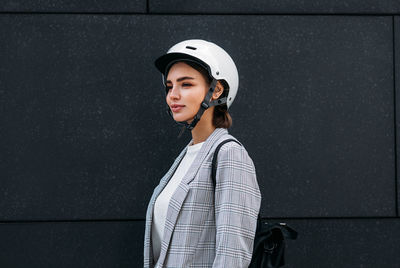 Portrait of young woman standing against wall