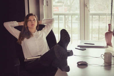 Portrait of young woman sitting on table at home