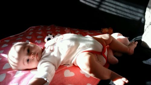 High angle portrait of baby lying on bed at home