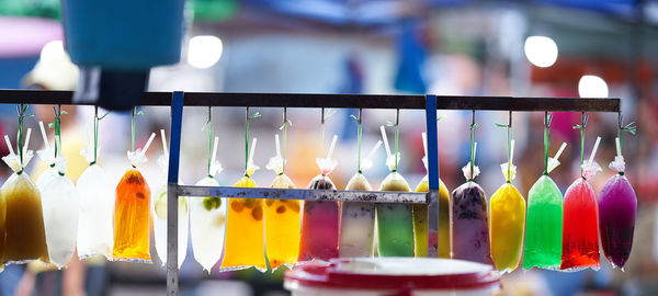 Close-up of multi colored drinks in plastic bags hanging at market stall