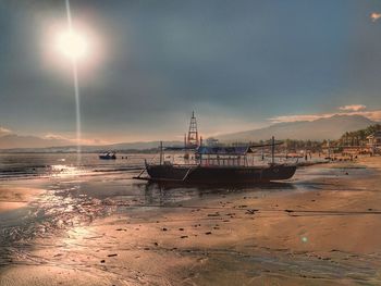 Sailboats moored on sea against sky during sunset
